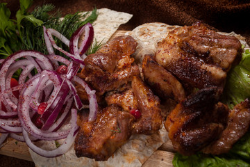 grilled barbecue meat served on a wooden Board with fresh vegetables and spices