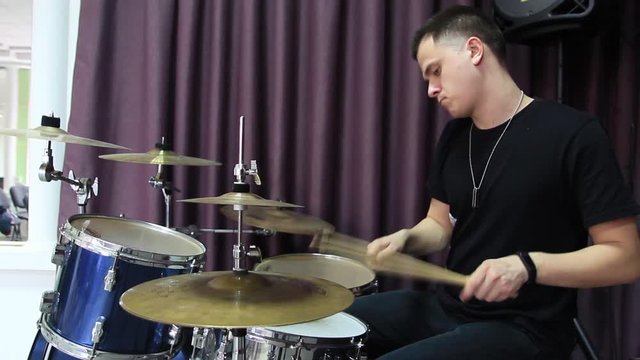 A young guy plays threes on hi-hat.
