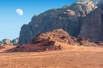  incredible lunar landscape with huge moon in Wadi Rum village in the Jordanian red sand desert....