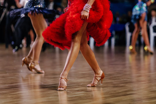 feet woman dancer in high heel shoes and red dress on dance floor