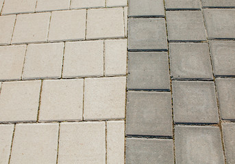 Black and grey cobblestones of a footpath have been laid in a geometrical pattern. They are worn with time