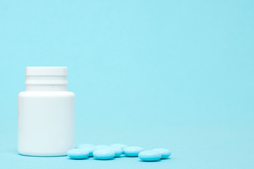 Blue pills and pill bottle on blue background