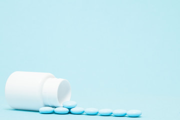 Blue pills and pill bottle on blue background