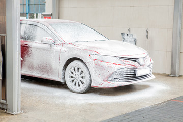Car wash with foam in car wash station. Carwash. Washing machine at the station. Car washing concept. Car in foam