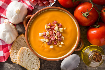 Typical Spanish salmorejo cream with ham and egg on wooden table. Top view. Copyspace