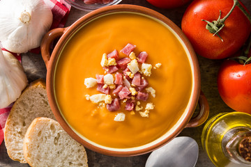 Typical Spanish salmorejo cream with ham and egg on wooden table. Top view. Copyspace