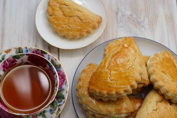Freshly baked sochni on white plates served with tea. White wooden background, high resolution