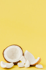close up fresh coconut pieces isolated on a yellow background, tropical fruit concept, flat lay, pop art, copy space