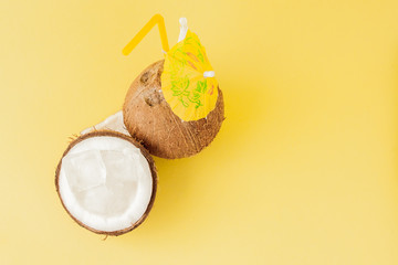 Fresh Coconut cocktail with a straws on yellow background, copy space