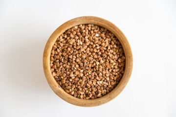 buckwheat groats in a wooden plate on a white background