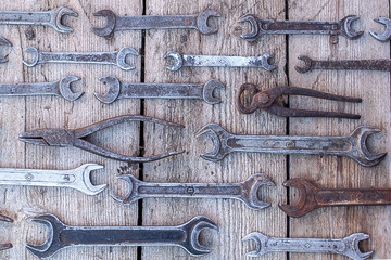 Metal wrench rusty tools lying on a black wooden table. Hammer, chisel, hacksaw, metal wrench. Dirty set of hand tools on a wooden panel vintage background with a tools