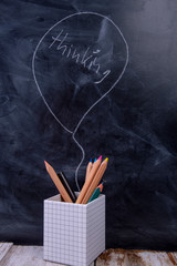 Wooden pens on a blackboard with the speech bubble Thinking