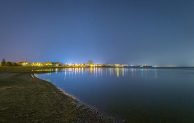 Lights of a small village on the beach at starry night