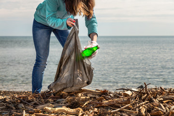 A young woman puts the collected garbage in the bag. Cleaning of the territory and environmental...