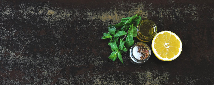 Fresh Lemon, Fresh Mint, Olive Oil, Salt And Spices On A Dark Surface. Copy Space. Set Of Seasonings For Cooking And Salads.