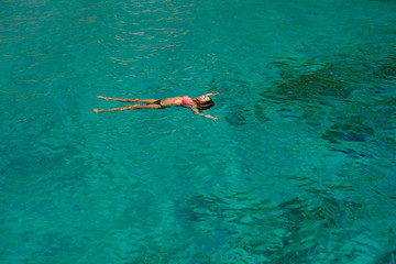 mujer joven flotando en el mar en bikini