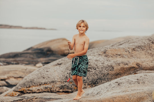 Boy standing on rocks fishing for crabs, Verdens Ende, Tjome, Tonsberg, Norway