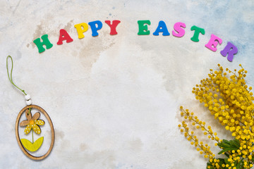 Easter background. Easter decoration, mimosa flowers and colorful letters forming words HAPPY EASTER. Copy space for your text.