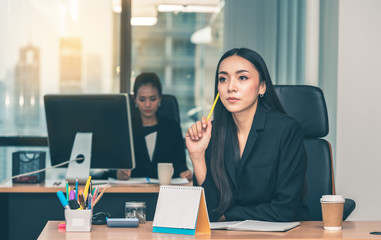 Asian business woman holding yellow pencil and thinking her job at the office