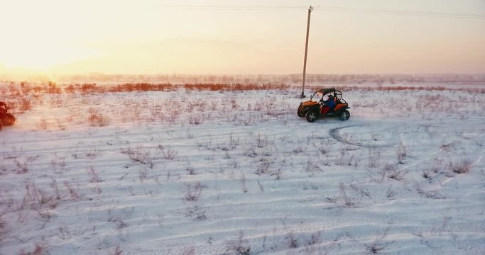 2 buggies ride against the sunset in winter