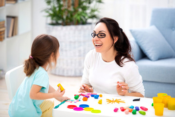 Obraz na płótnie Canvas How to save healthy eyesight. Mom and daughter make glasses from plasticine