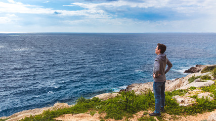 Man stands on the edge of the abyss and looks at the sea