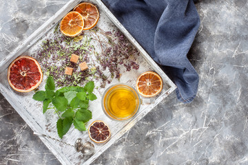 Herbal tea on wooden tray with dry grass and fresh mint