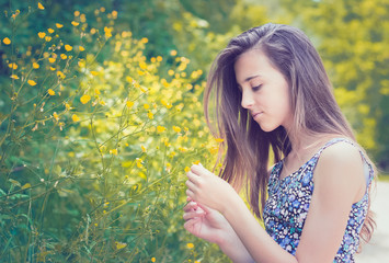Closeup photo of a young lady in floral dress caressing flowers. Enjoying the nature and beautiful, sunny day, carefree
