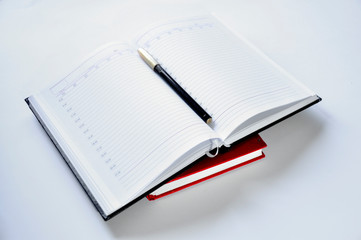 Open notebook. Black pen. On white background.
