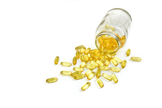 Close up of Gold fish oil capsules isolated in jar glass on white background. Salmon fish capsules view. Omega 3. Vitamin E. Supplement food background.