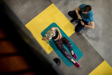 Foto op Canvas Top view at sporty woman exercises with assistance of her personal trainer © BGStock72