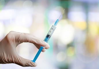 Human Hands with injection Syringe, on blurred background.