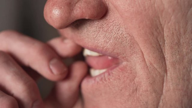 The mouth of an elderly man with false teeth. An older man pulls his upper jaw out of his mouth. Grandpa takes off his false teeth. Mouth close up, slow motion, 4K