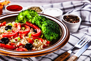 Groats with vegetables on wooden table
