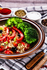 Groats with vegetables on wooden table