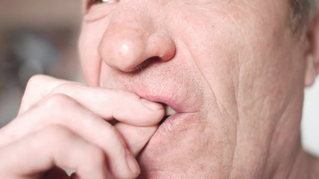 The mouth of an elderly man with false teeth. An older man inserts his upper jaw into his mouth. Grandfather with false teeth. Mouth close up, slow motion, 4K