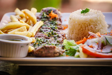 steak served in a restaurant dish with frites and rice