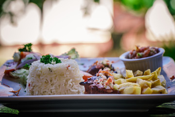 steak served in a restaurant dish with frites and rice