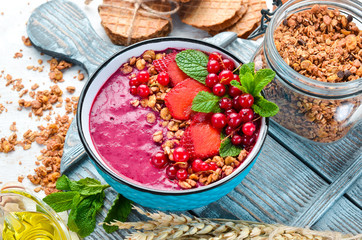 Smoothie bowl with granola, strawberry, red currants and mint. Breakfast. Top view. Free space for your text.