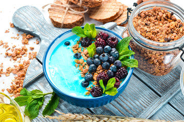 Blue Spirulina and Fresh Fruit Smoothie Bowl Topped with blackberries, blueberries, granola and yogurt. Breakfast. Top view. Free space for your text.