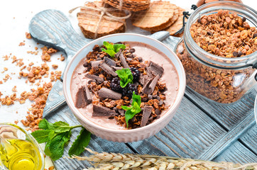 Fresh breakfast with yogurt, granola, chocolate and berries in a bowl. Top view. Free space for your text.