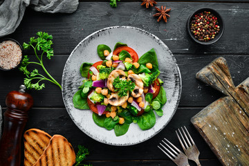 Salad with mushrooms, spinach, Turkish peas and onion in a plate on a wooden background Top view. Free space for your text. Flat lay