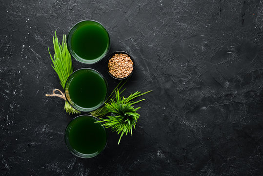 The juice from the green sprouted wheat, and wheat grains. On a black background. Micro Green. Healthy food. Top view. Free space for your text.