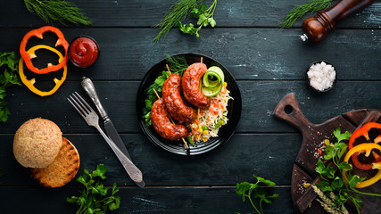 Baked sausages with rice. In a black plate. Top view. Free copy space.