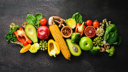 Foods containing natural fiber: avocados, kiwi, apple, tomatoes, spinach, paprika, orange, lemon. Top view. Free space for your text. On a brown background.