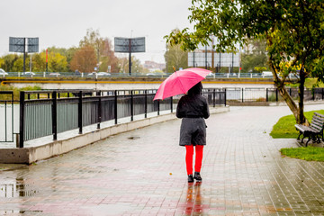 Woman with red umbrella in city park during rain_