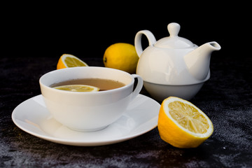 Teapot and cup of tea with fresh lemon.
