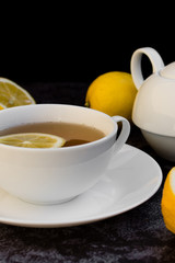 Teapot and cup of tea with fresh lemon.