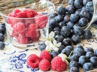 raspberries and blueberries in bowl on wooden table
