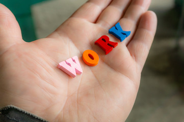 Multi-colored letters word work on a man's hand.